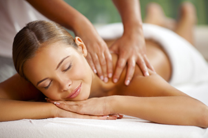 Young happy woman receiving shoulder massage at spa and beauty salon