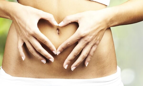 A woman's stomach with her hands making a heart shape, Get $20 Off Colonic.